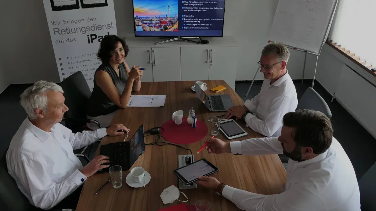 Vier Herrschaften an einem Konferenztisch in einem Investitionsgespräch.