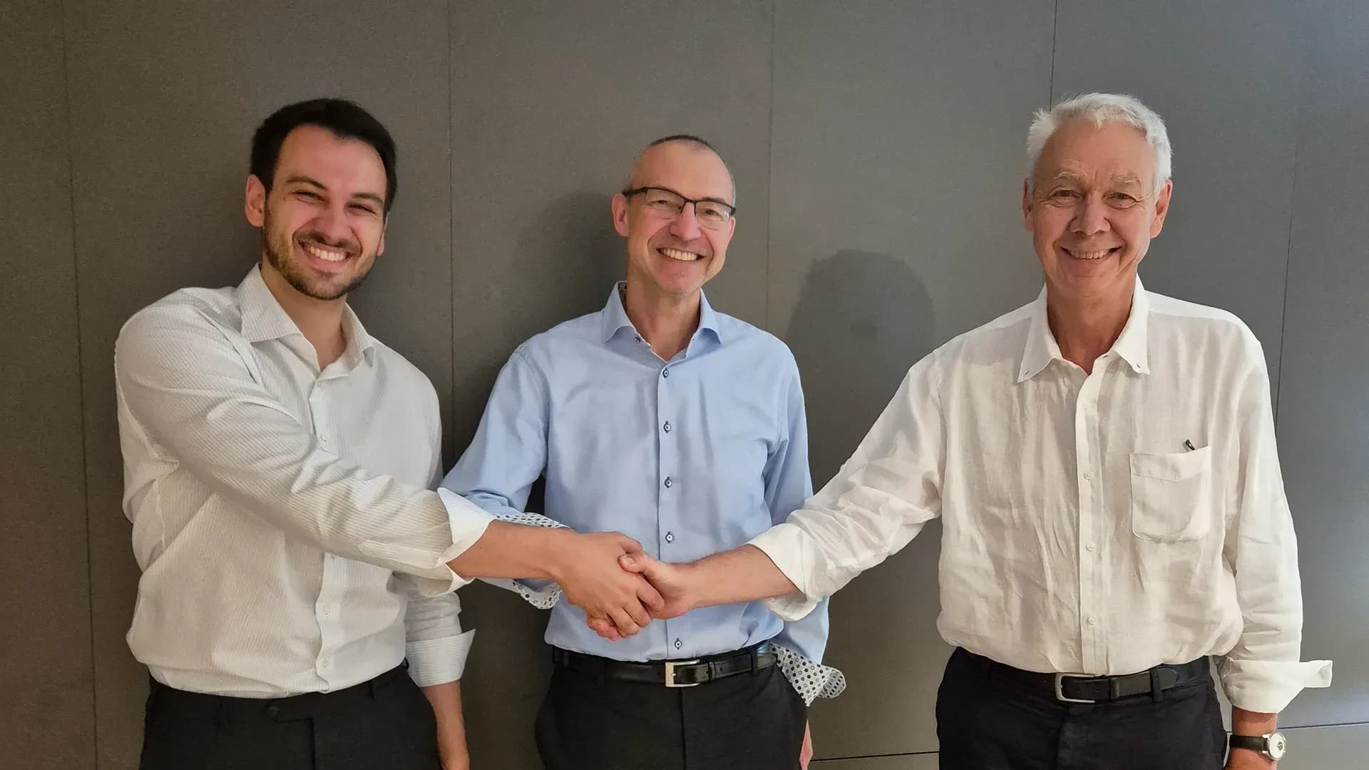 Drie mannen bezegelen de overname van ASSD GmbH met een handdruk